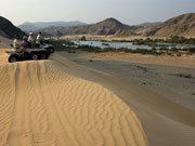 A quad-biking expedition at Serra Cafema Camp, Kunene River, Namibia, pauses for a moment to enjoy the view over the river valley.