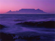 Dawn pains the surf purple as the sky turns pink over Table Mountain, Cape Town, South Africa.